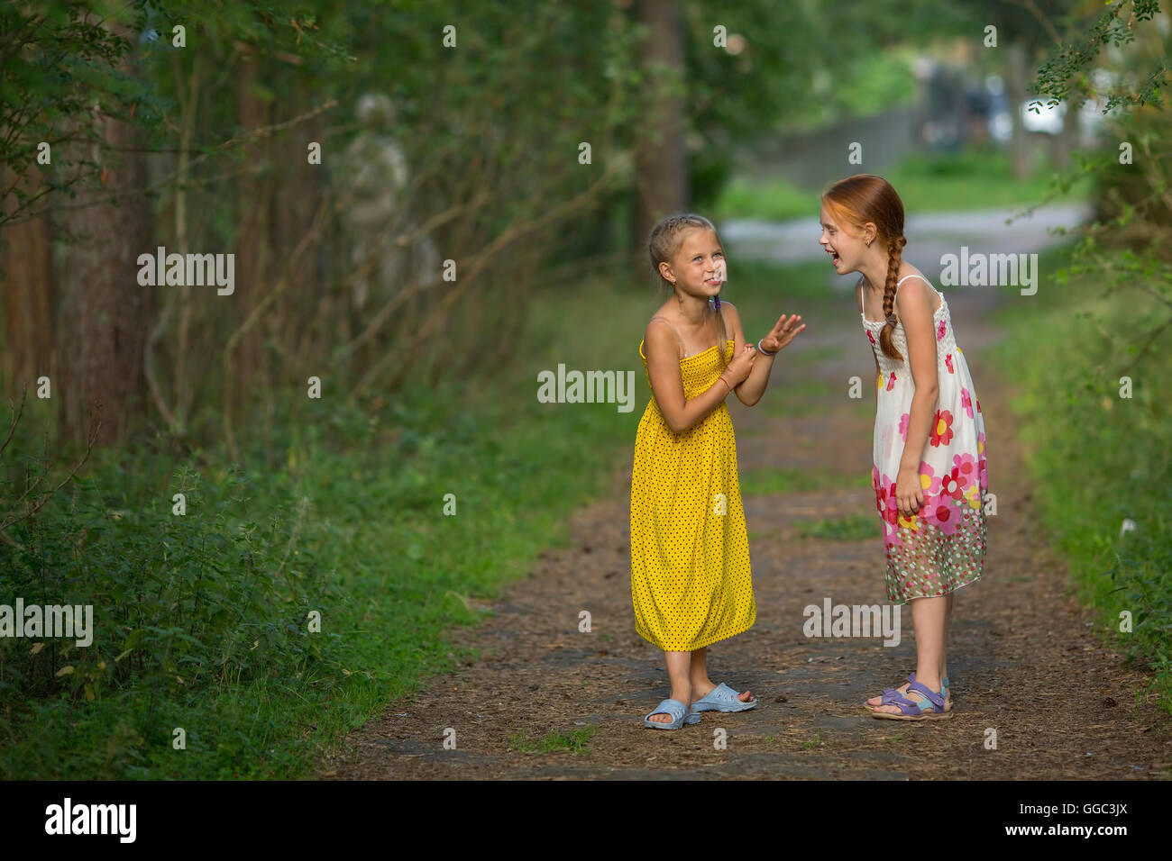 Deux mignonnes petites filles discutaient avec animation de standing dans un parc. Banque D'Images