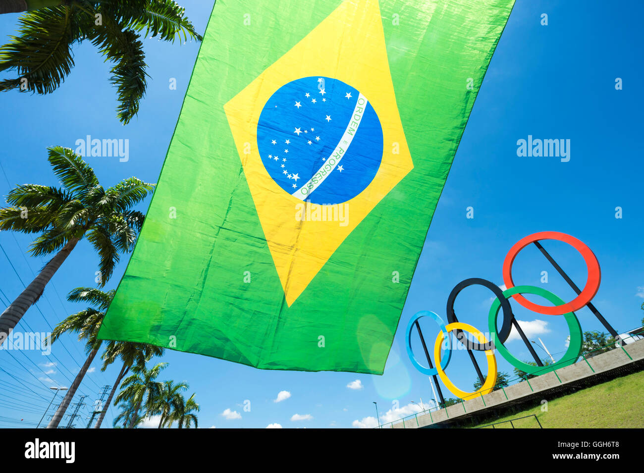 RIO DE JANEIRO - le 18 mars 2016 : un drapeau du Brésil s'arrête en face de l'affichage des anneaux olympiques dans la région de Parque Madureira Park. Banque D'Images