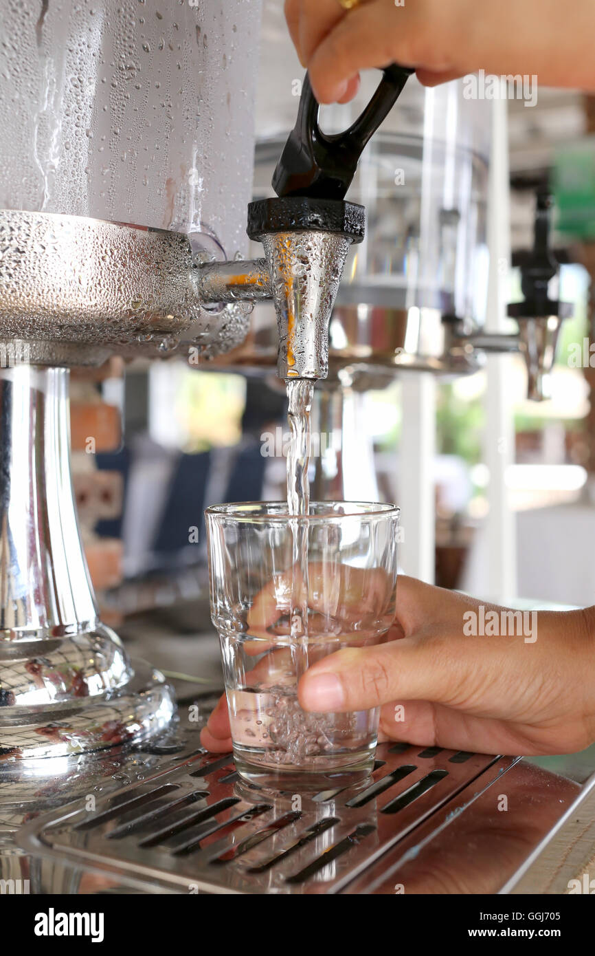 La femme avait les mains appuyant sur l'eau fraîche en verre dans un restaurant. Banque D'Images