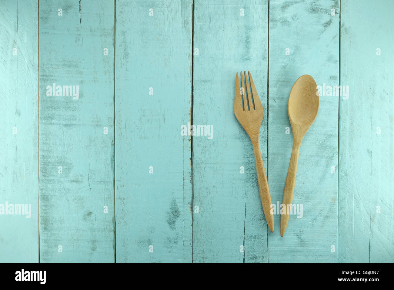 Cuillère en bois et une fourchette placée sur un fond de bois vert pour des concepts de design dans l'alimentation santé. Banque D'Images