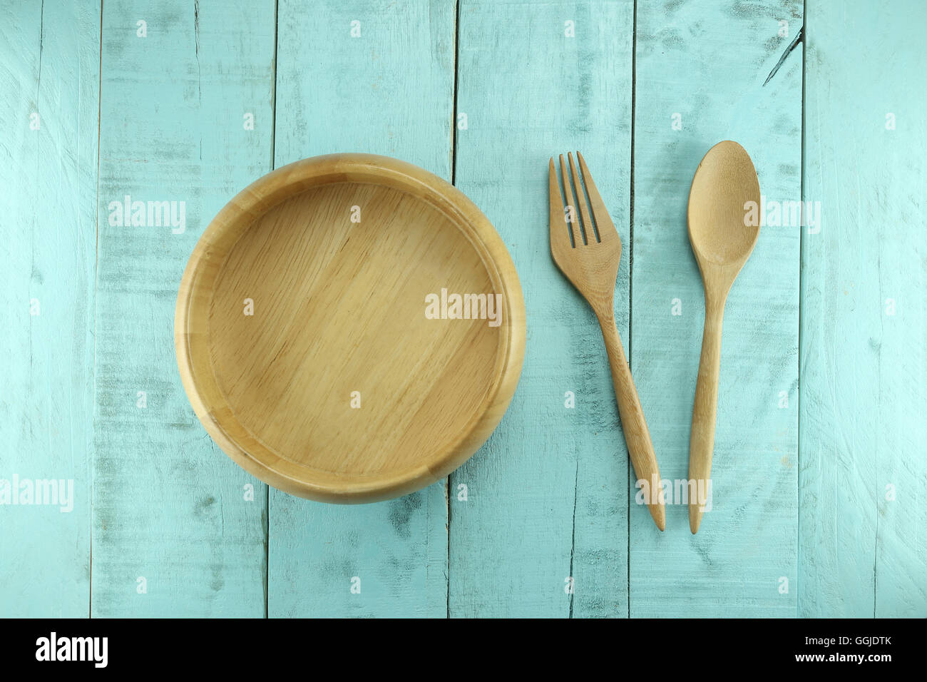 Cuillère en bois et la fourchette placé près de bol sur un fond de bois vert pour des concepts de design dans l'alimentation santé. Banque D'Images