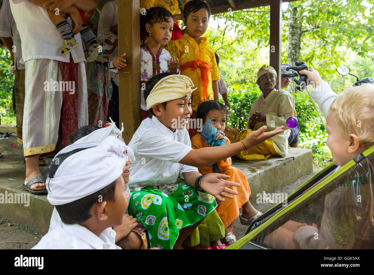 Les enfants balinais jouant avec l'Allemand jeune garçon, 3 ans, vêtements traditionnels à la cérémonie du temple, la religion balinaise, poussette, je Banque D'Images