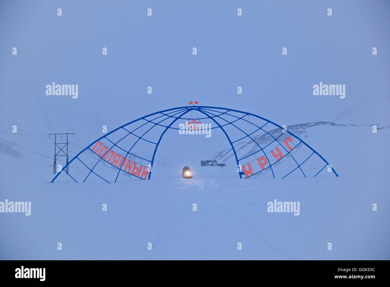 Dans une tempête de la conduite de motoneige à travers une arche en acier, monument marquant l'intersection de la calotte polaire nord cercle avec le Banque D'Images