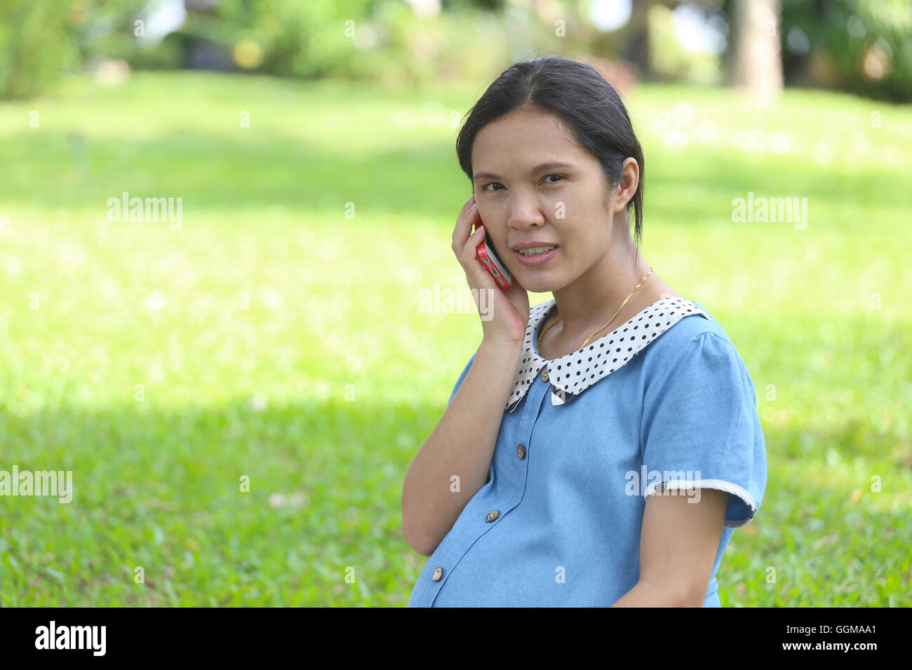 Les femmes enceintes asiatiques using smartphones appel à médecin et sur requête dans les soins de santé dans le parc public. Banque D'Images