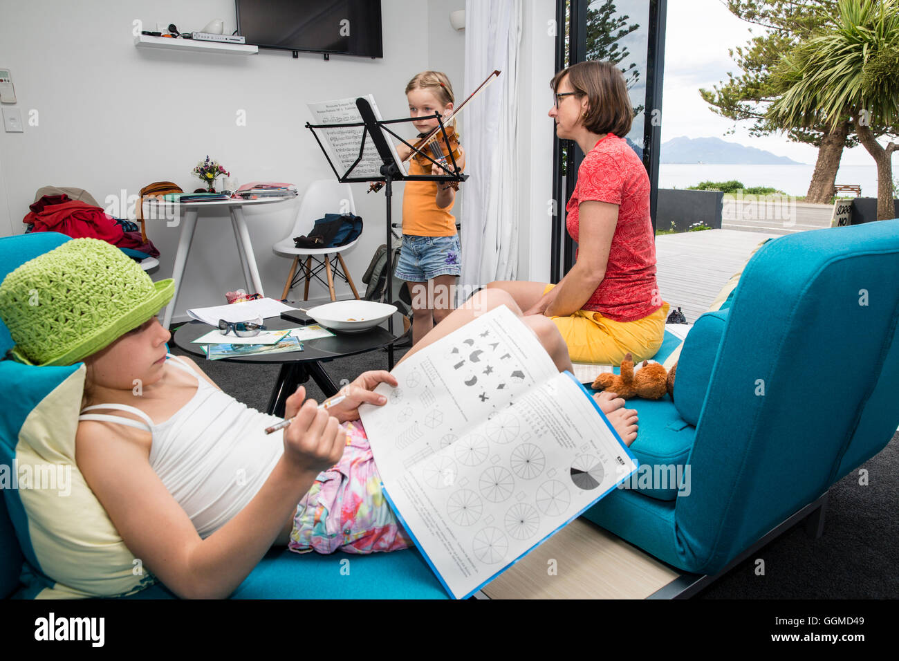 Deux filles faisant leurs devoirs, l'un joue du violon, Kaikoura, île du Sud, Nouvelle-Zélande Banque D'Images