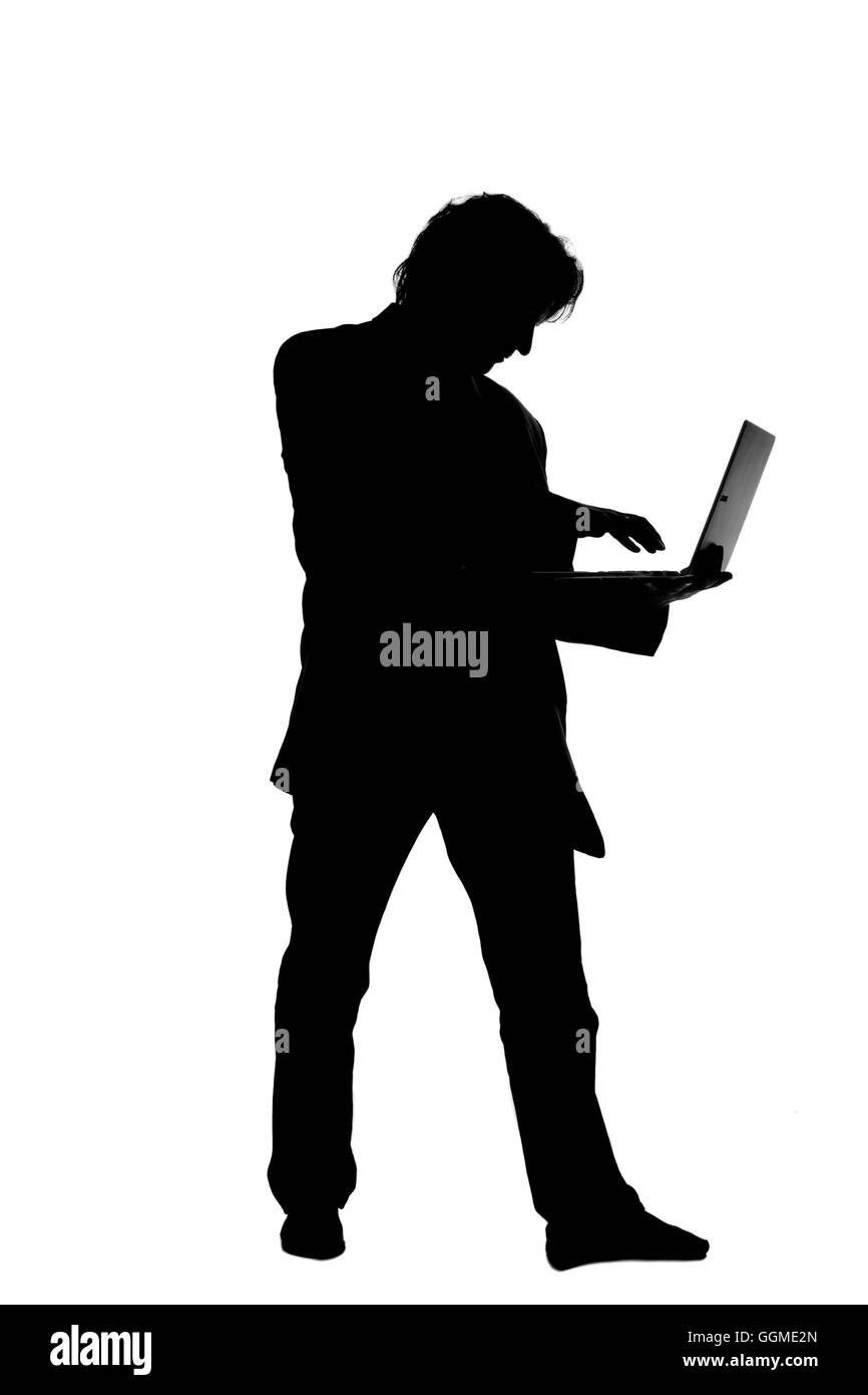 Silhouette d'un homme en fonction de la saisie sur un ordinateur portable Banque D'Images