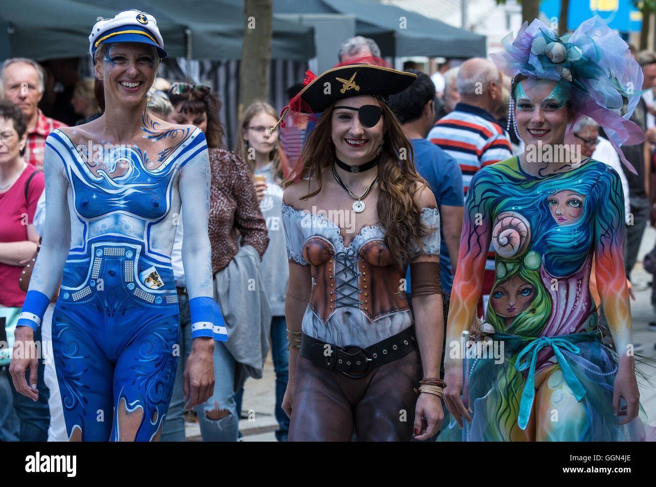 Wilhemshaven, Allemagne. Le 06 août, 2016. Joana modèles comme 'Sailor' (L-R), Melanie comme "pirate" et Janina comme 'coral reef' à pied à travers la zone piétonne après des heures de bodypainting au Street Art Festival à Wilhemshaven, Allemagne, 06 août 2016. Autour de 40 peintres dans la rue, artistes 3D et bodypainters de partout dans le monde prennent part à la 6e Festival International de Street Art sur le Jade Bight. Photo : INGO WAGNER/dpa/Alamy Live News Banque D'Images