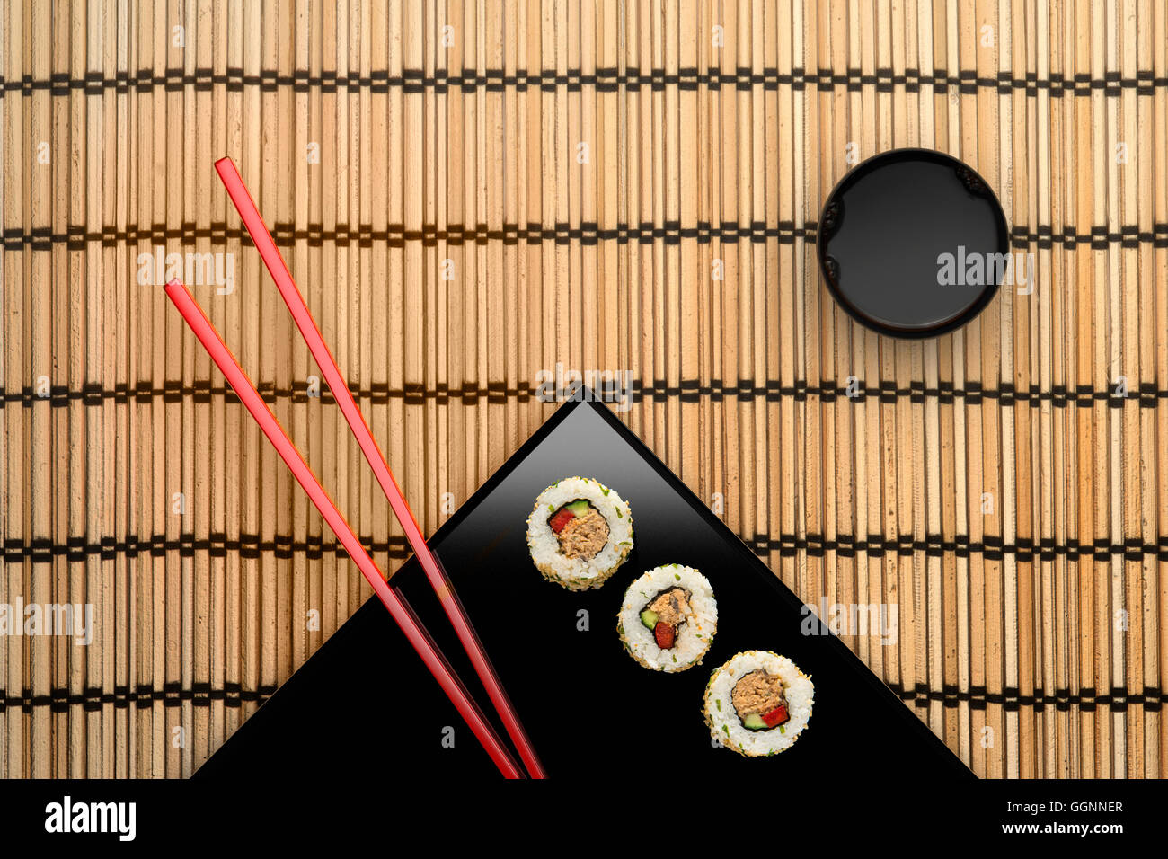 Baguettes et sushi sur plaque carrée avec sauce Banque D'Images