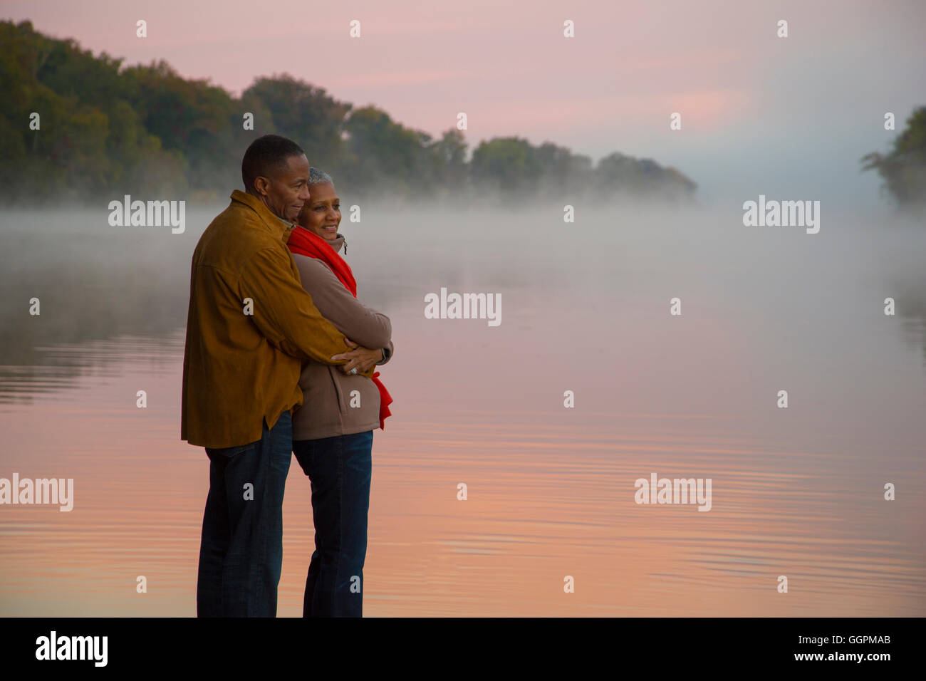 Vieux couple hugging at foggy river au lever du soleil Banque D'Images