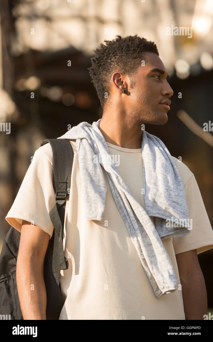 Mixed Race man avec sac à dos et shirt drapé sur les épaules Banque D'Images