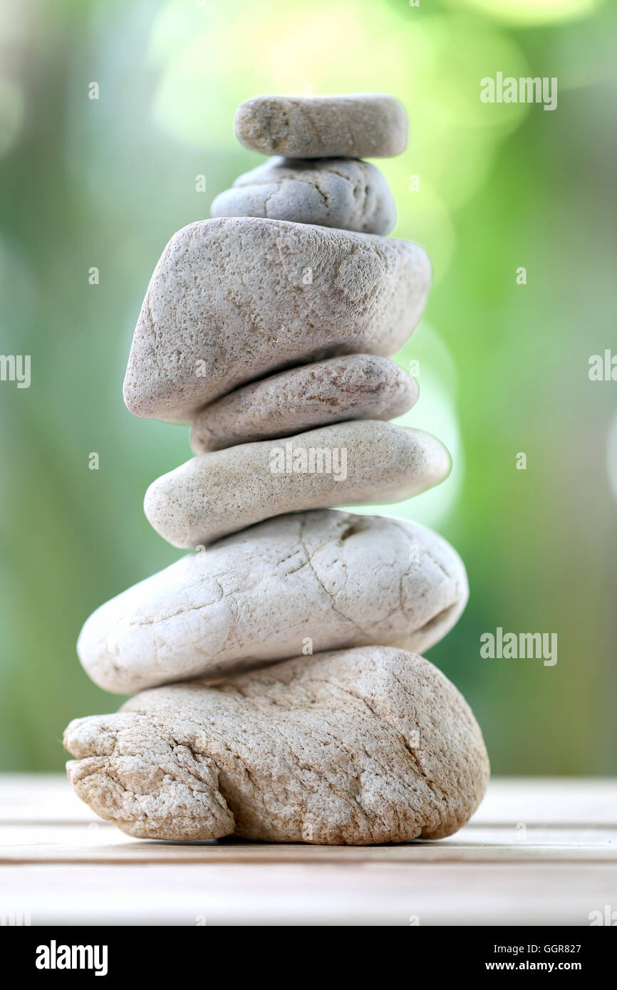 Rock balance ou zen stones sur plancher en bois et ont un fond vert nature in soft focus. Banque D'Images