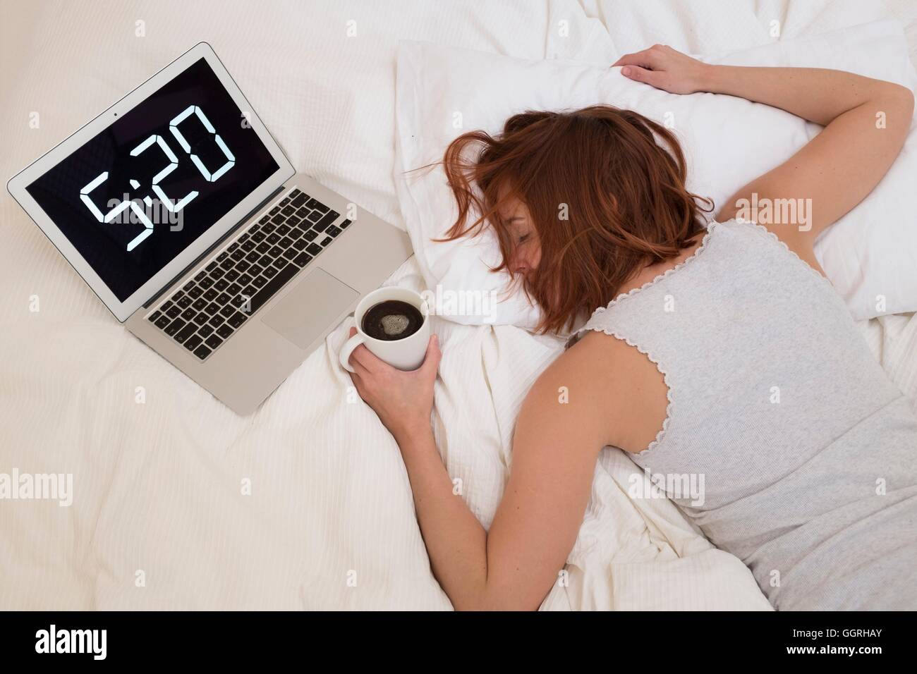 Épuisé femme au lit avec coffre et du café. Banque D'Images