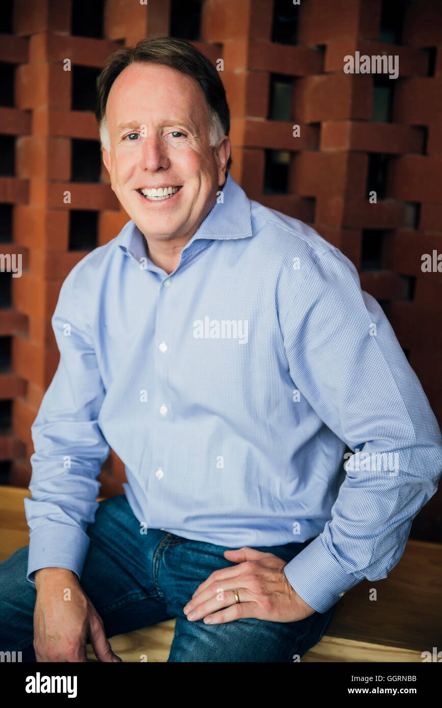 Smiling Caucasian man wearing jeans assis Banque D'Images