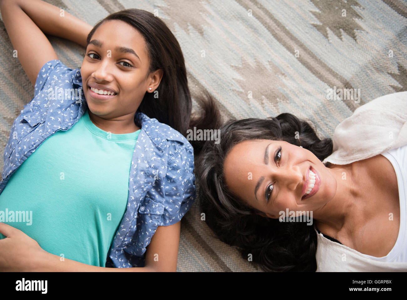 Smiling mother and daughter portant sur un tapis Banque D'Images