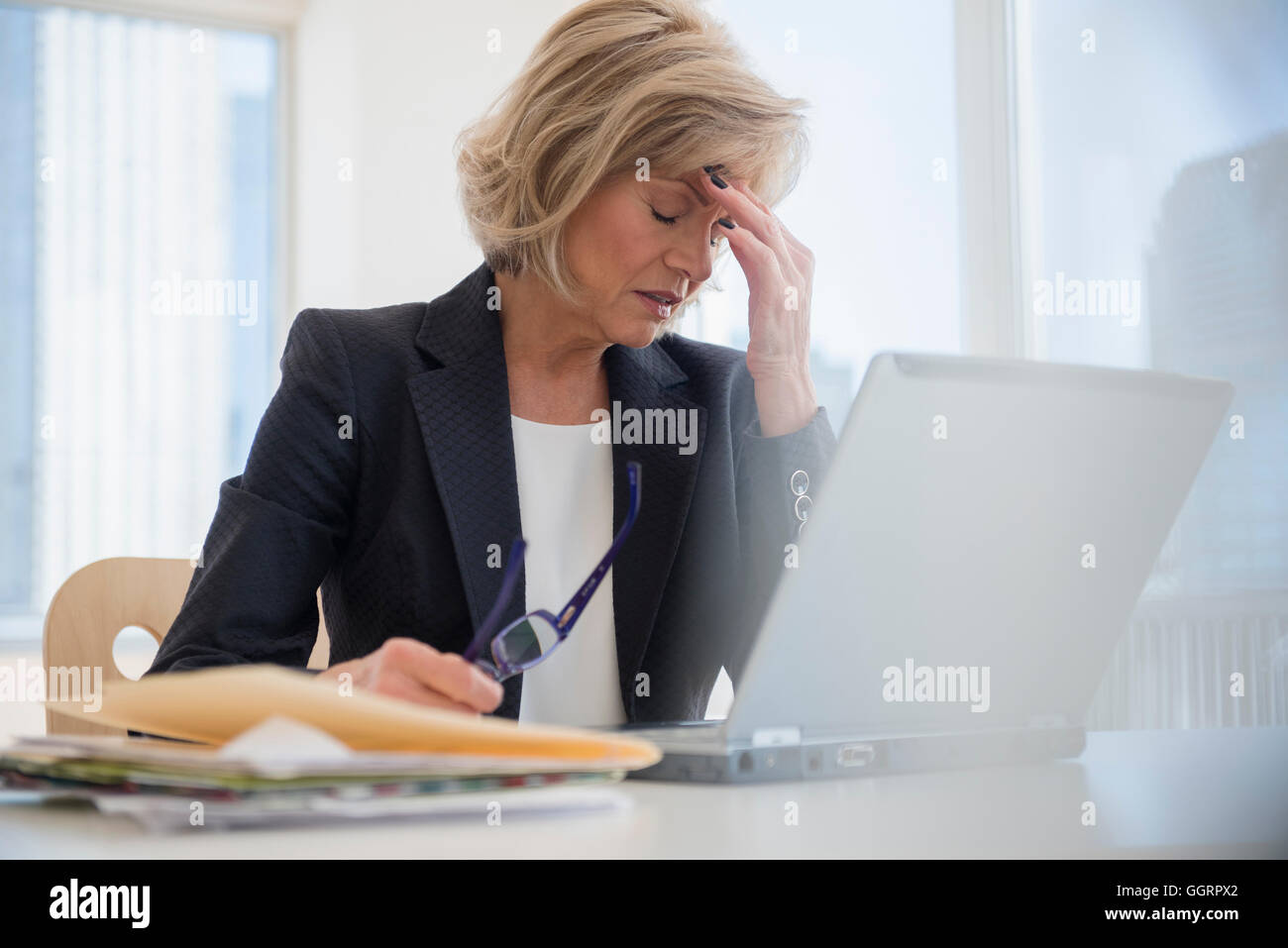 Caucasian businesswoman avec maux using laptop Banque D'Images