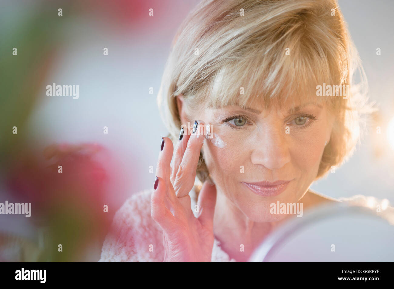 Older Caucasian woman applying moisturizer à face Banque D'Images