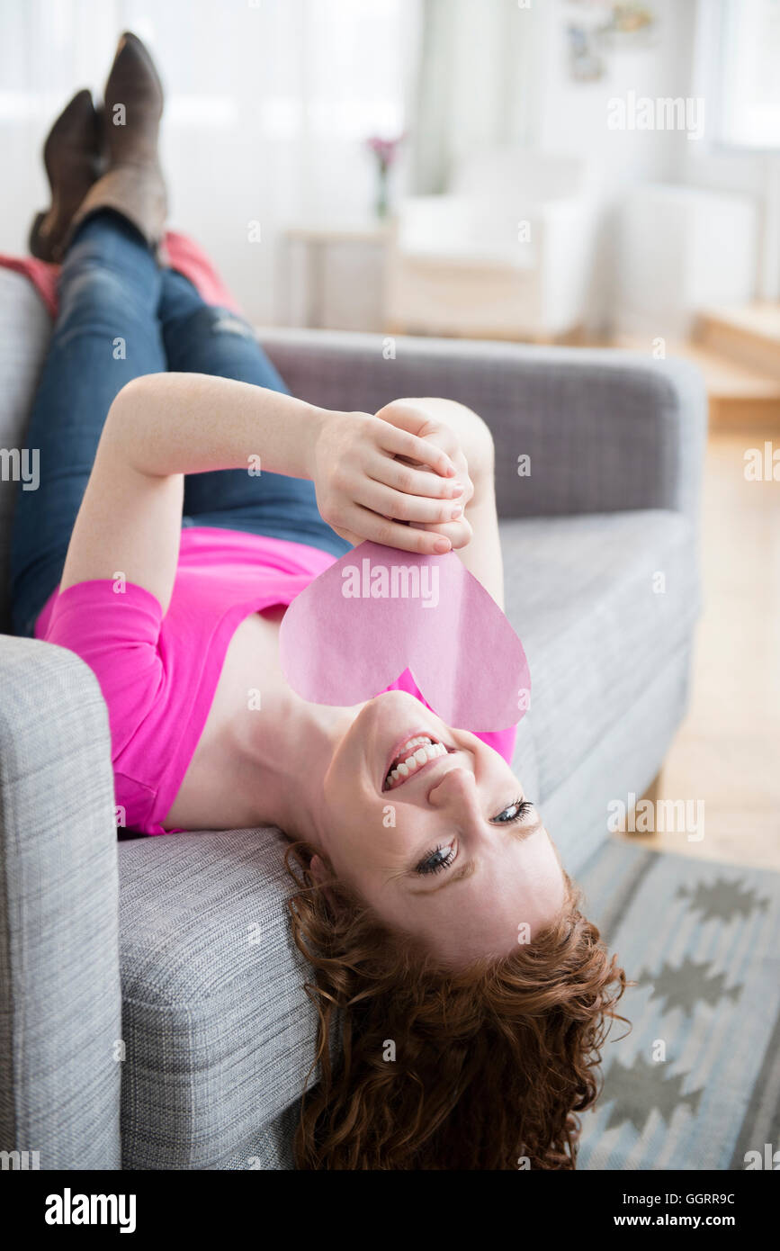 Caucasian woman laying on sofa holding valentine Banque D'Images
