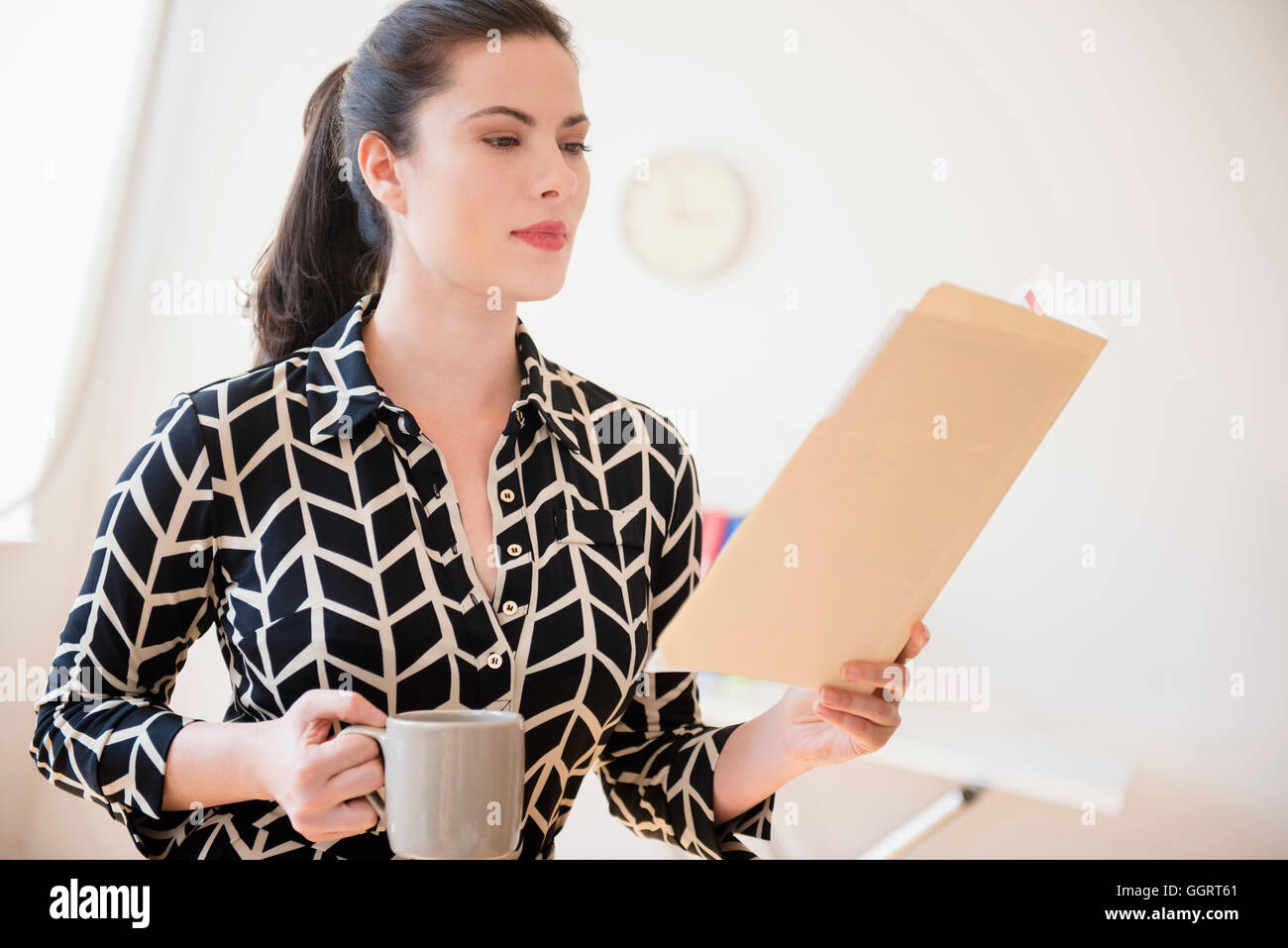 Caucasian businesswoman reading paperwork in fichier dossier Banque D'Images