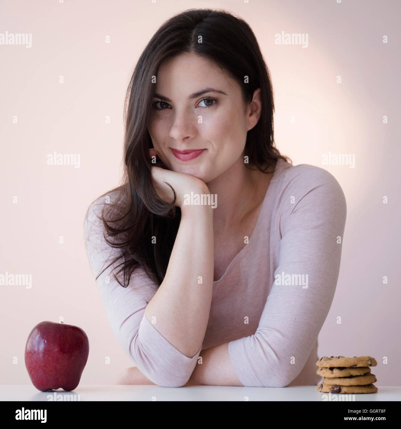 Caucasian woman choisir entre Apple ou les cookies pour le goûter Banque D'Images