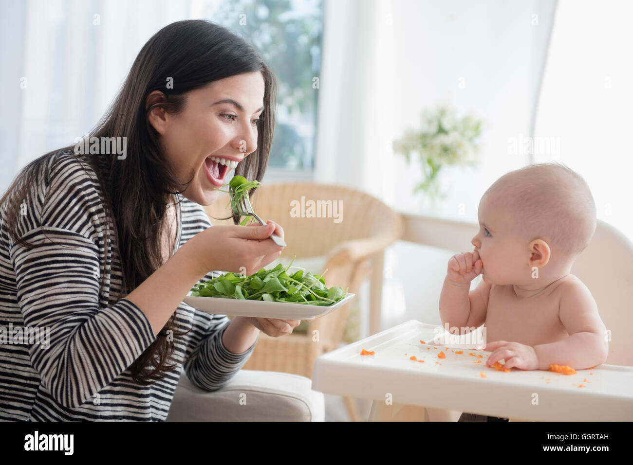 Young woman eating salad tout en regardant sa petite fille Banque D'Images