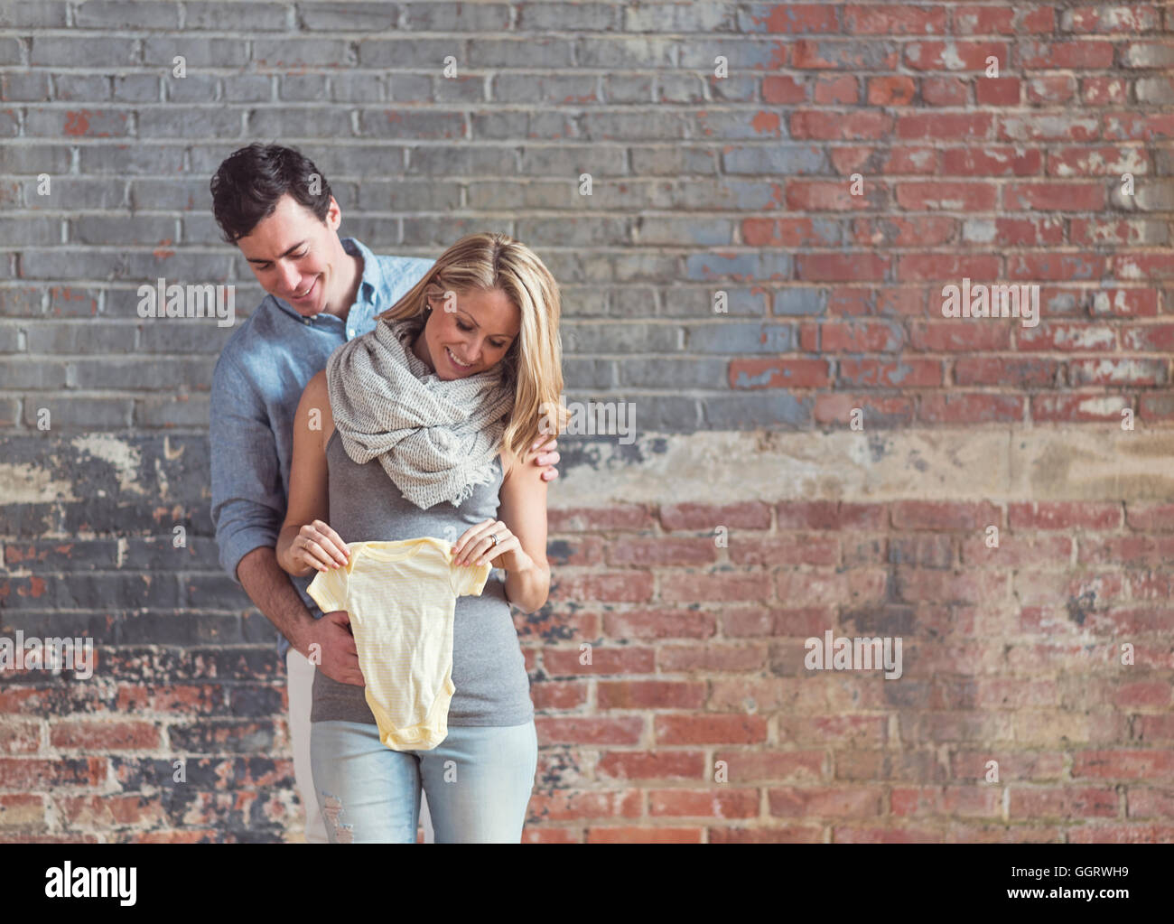 Smiling Caucasian man et future mère holding onesie Banque D'Images