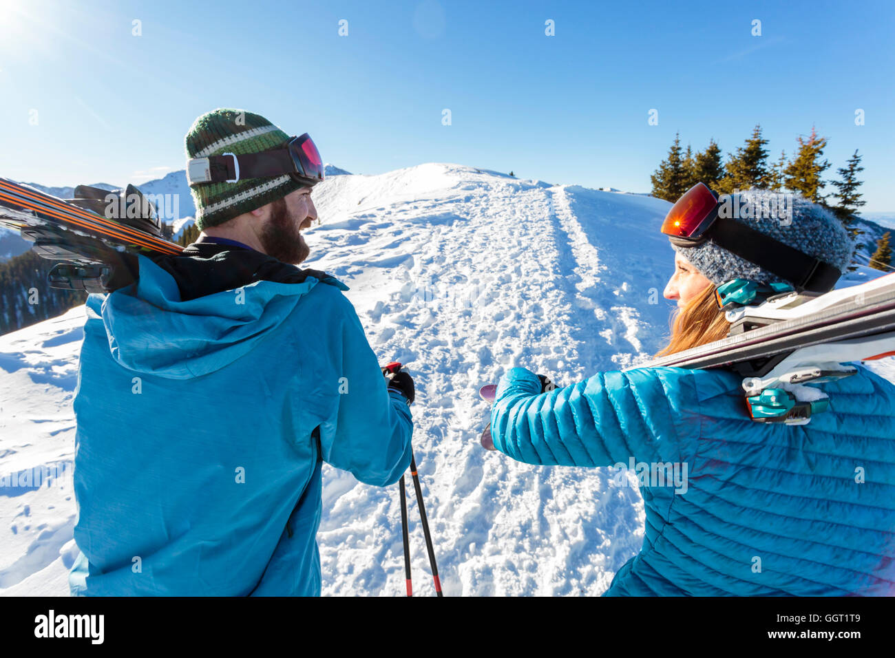 Couple carrying skis on snowy mountain Banque D'Images