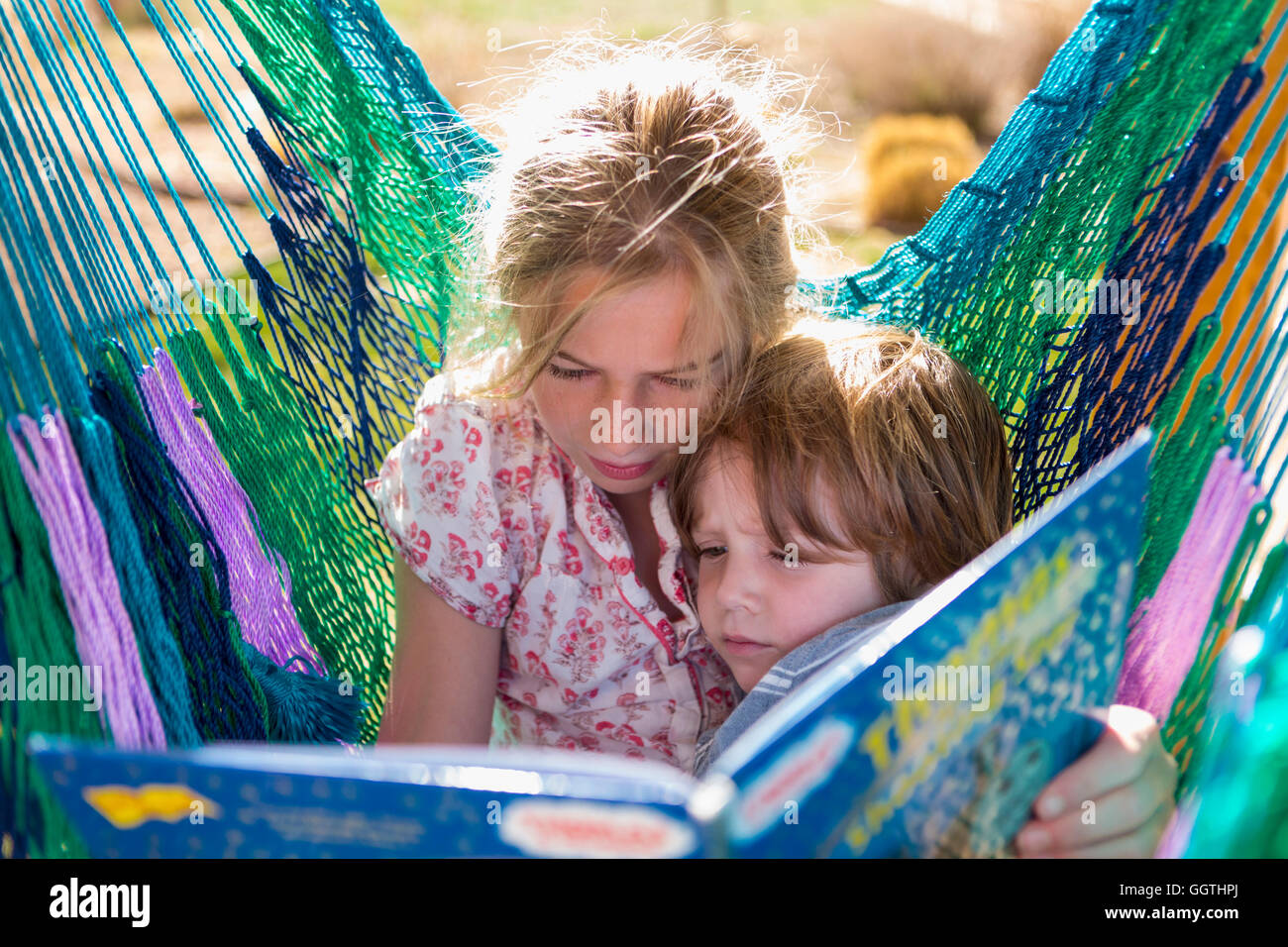 Portrait de frère soeur reading book in hammock Banque D'Images