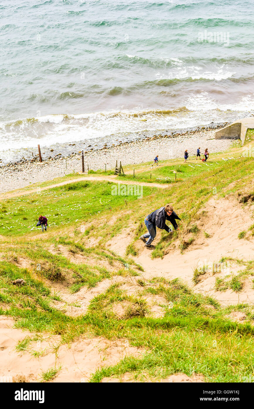 Kaseberga, Suède - août 1, 2016 : Young adult man and woman grimper une pente de la côte de sable de la mer ci-dessous. Situation de la vie réelle Banque D'Images