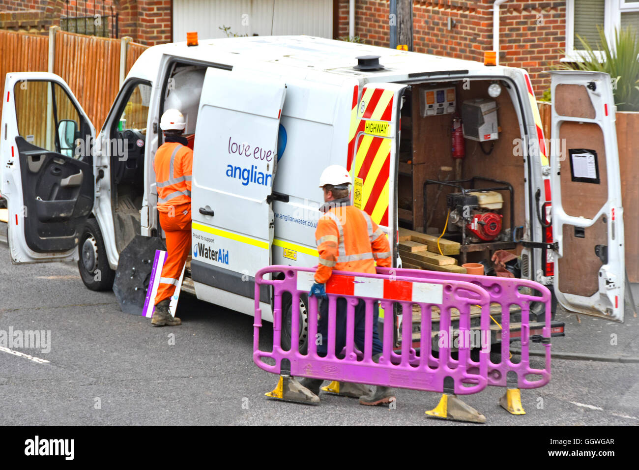 Anglian Water crew & van fréquentant UK Angleterre street raccordé à la préparation de la propriété résidentielle de déterrer road repoussant les barrières en position Banque D'Images