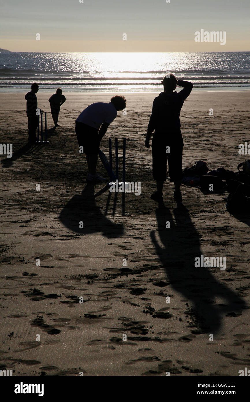 Seulement sur une plage anglaise... ces chiffres en silhouette jouent un jeu d'été typiquement anglais de Cricket. Banque D'Images