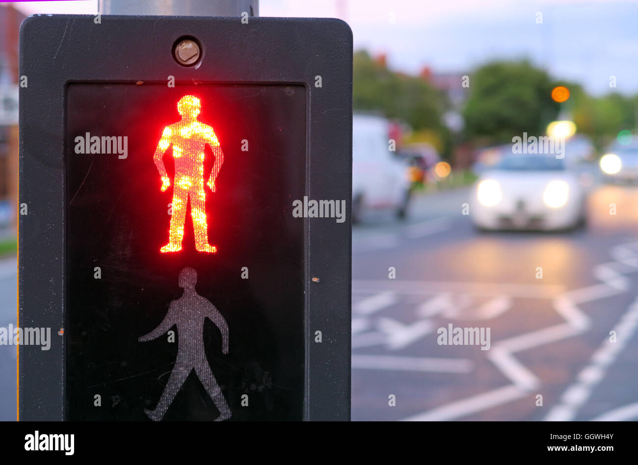 Homme rouge au Royaume-Uni, passages protégés avec soirée le trafic en arrière-plan Banque D'Images