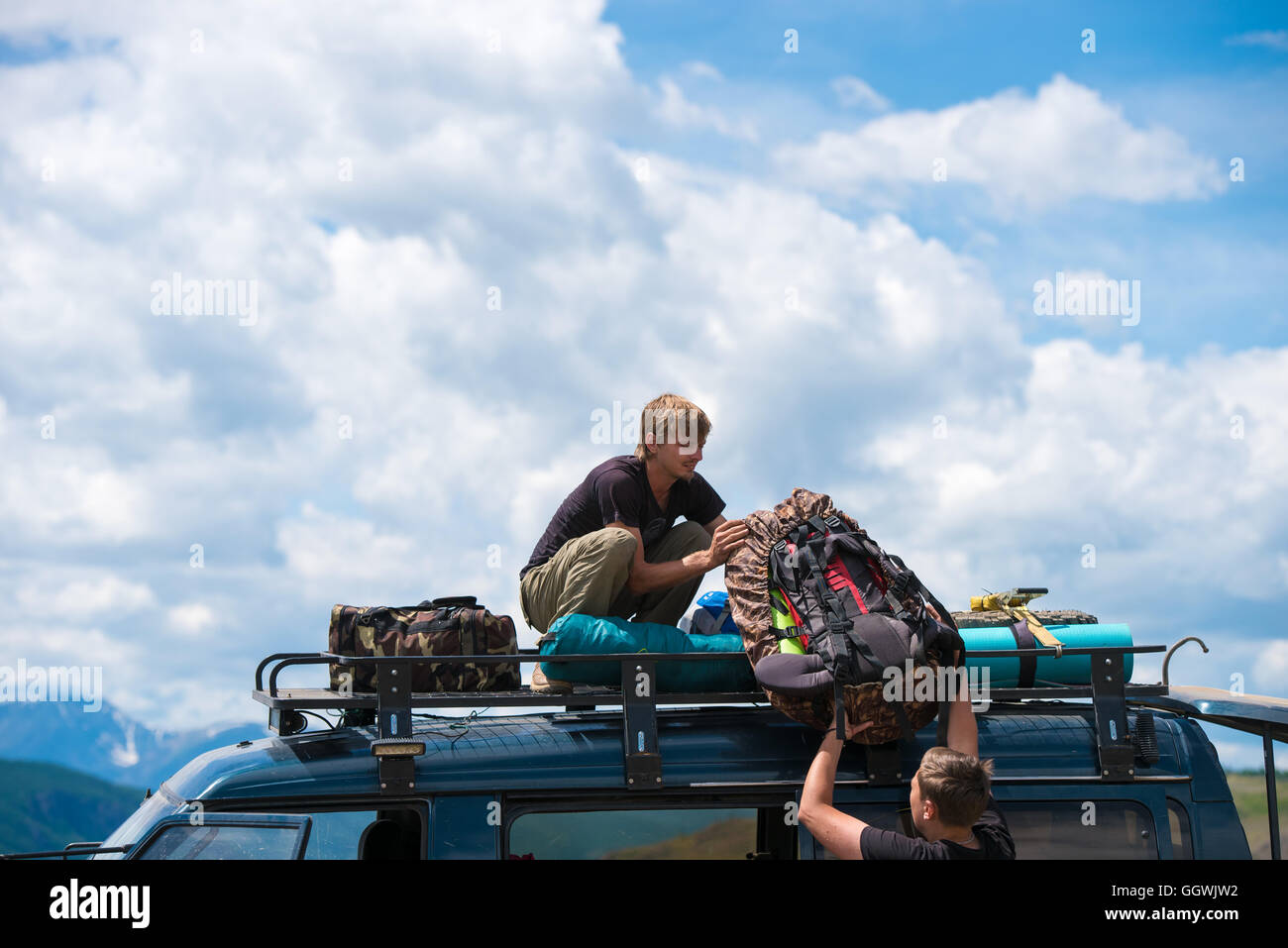 L'homme donne à un autre homme d'un sac à dos sur le toit de la voiture Banque D'Images