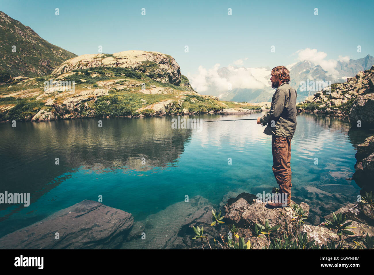 L'homme pêche pêcheur avec rod lac et montagnes sur fond de vie Voyages loisirs concept active summer vacations Banque D'Images