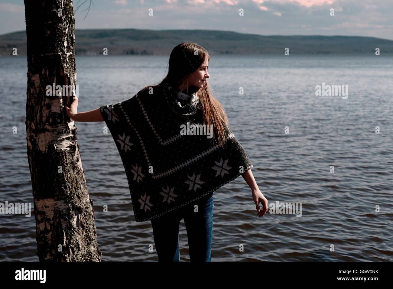 Caucasian girl leaning on tree trunk au lac Banque D'Images