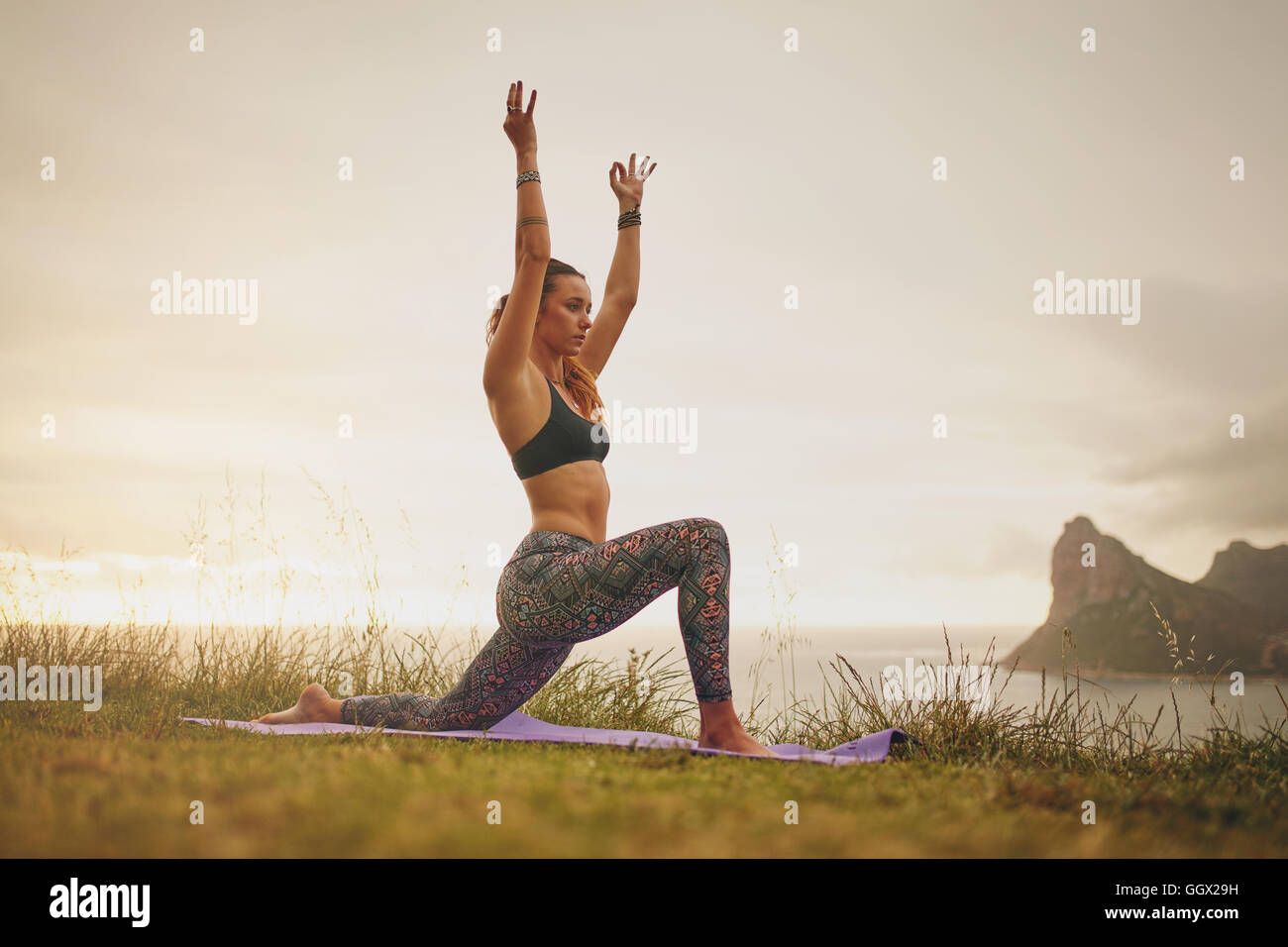 Vue de côté tourné de forme libre sur falaise. Woman practicing yoga musculaire posent à l'extérieur. Banque D'Images