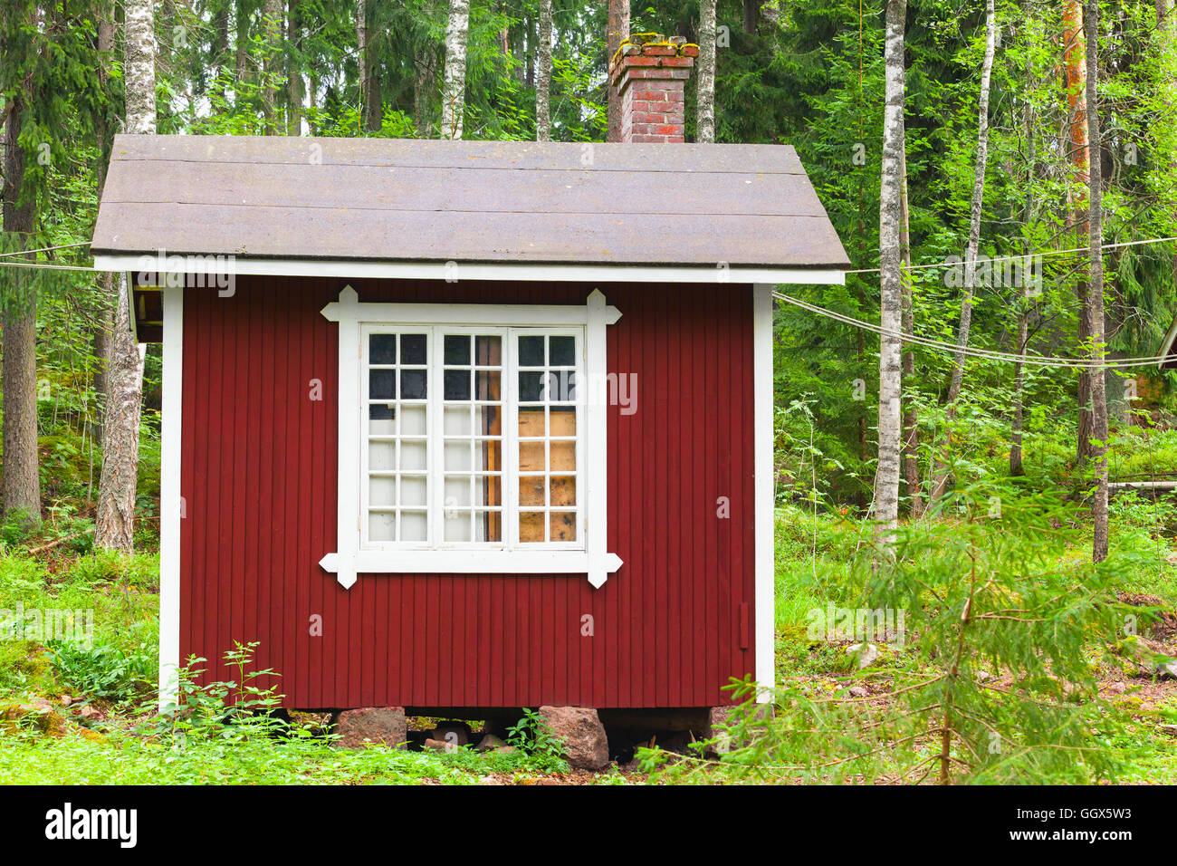 Petite maison en bois rouge scandinave sur fond vert de la forêt. Kotka, Finlande Banque D'Images