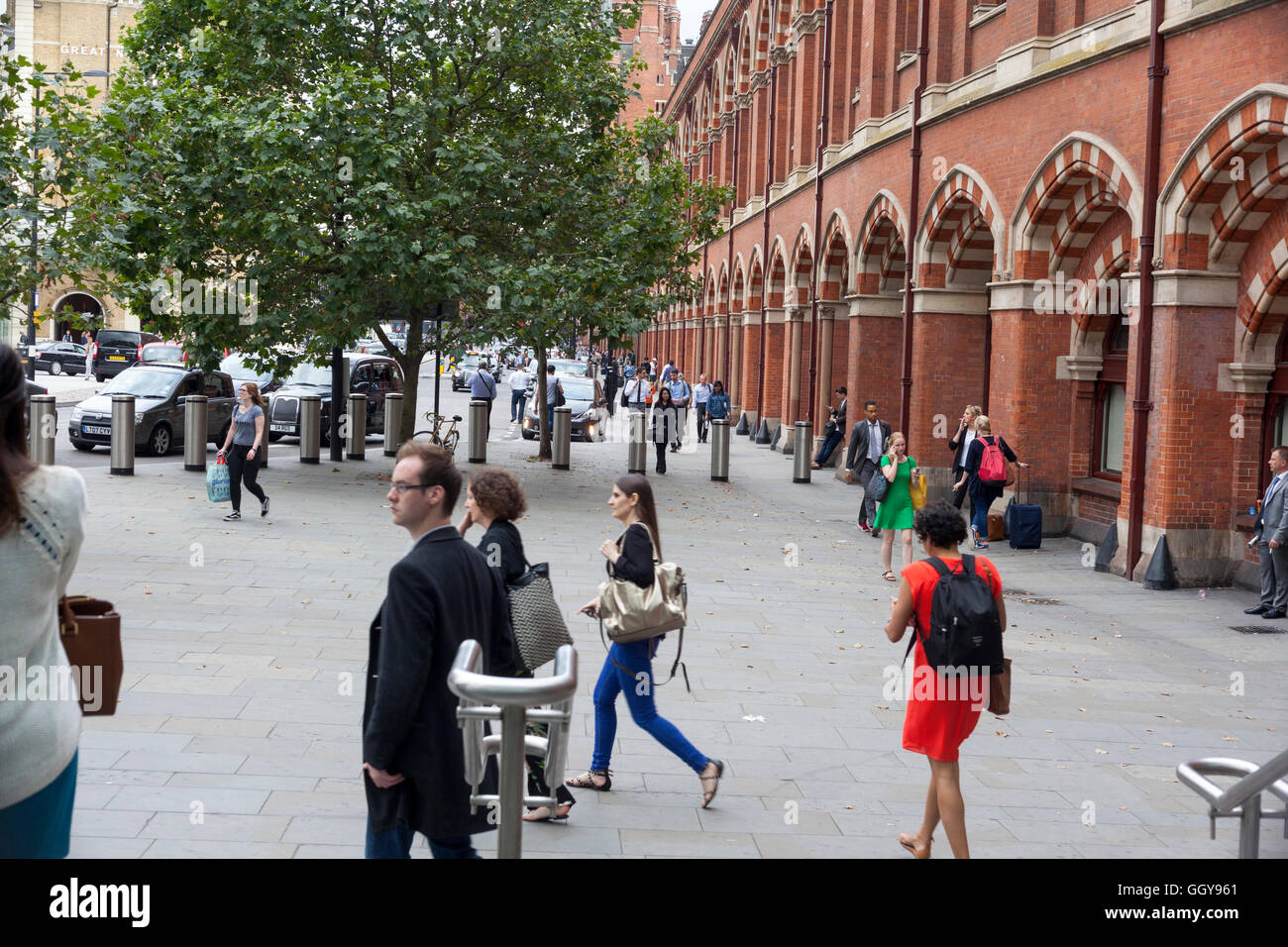Les personnes occupées qui vaquent à leurs activités à l'été sur le trottoir devant la gare de St Pancras Banque D'Images