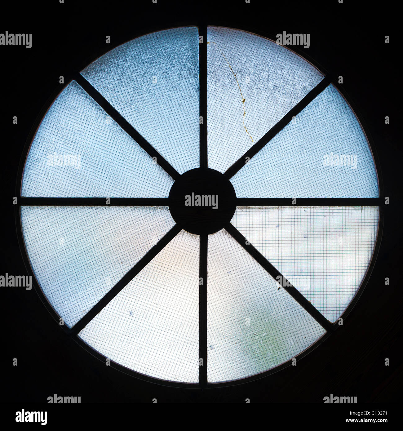 Petite fenêtre ronde avec grille sur fond noir Banque D'Images