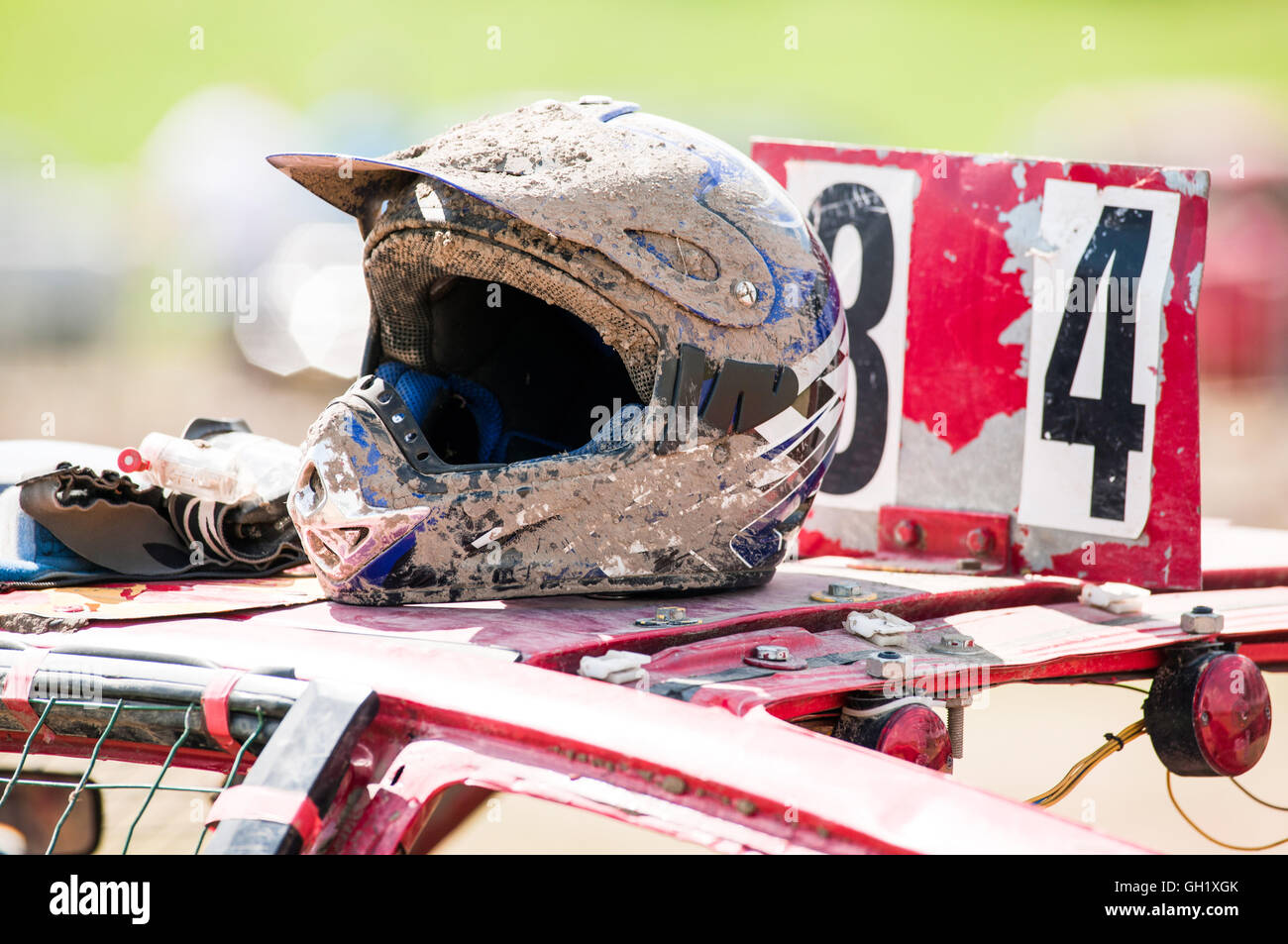 Casque avec la boue allongé sur le toit d'une voiture de stock après une course tenue Banque D'Images