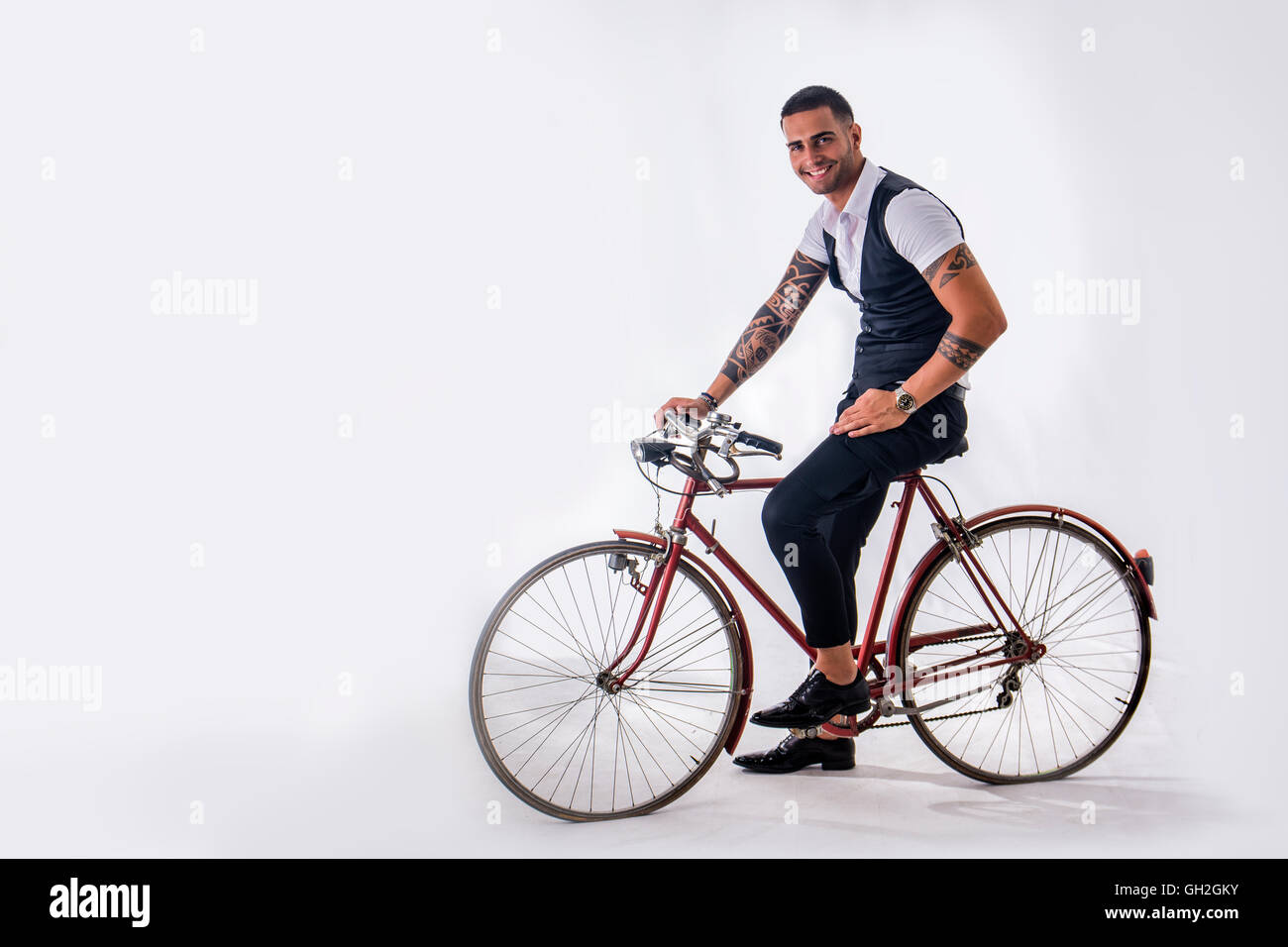 Portrait de jeune homme tatoué dans d'élégants vêtements et chaussures de la bicyclette.Isoler.Studio shot. Banque D'Images