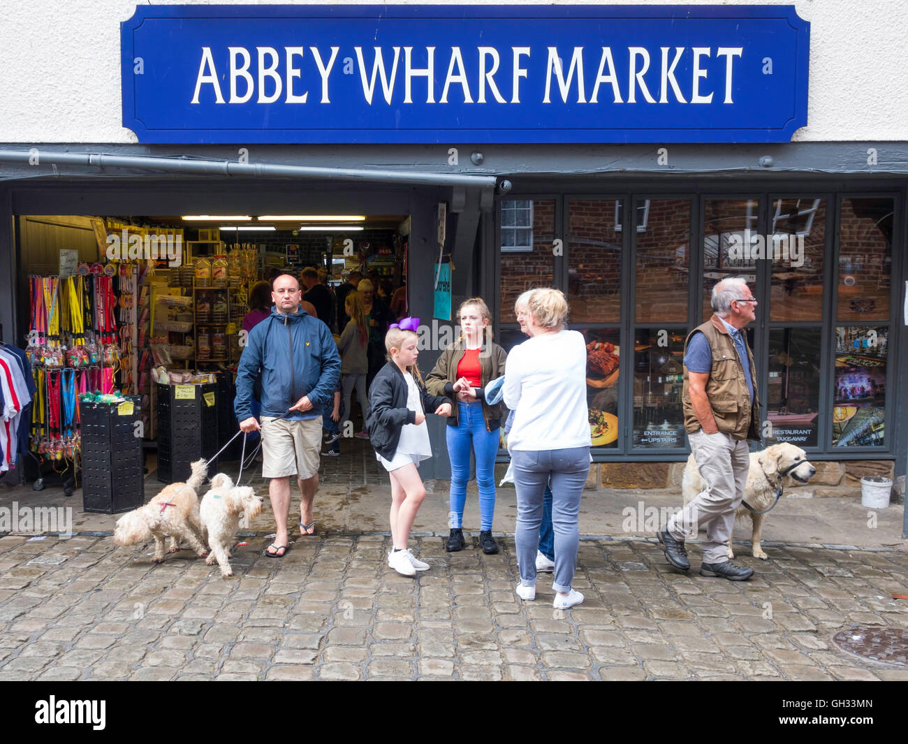 Groupe familial avec des chiens à l'extérieur de l'abbaye Place du Marché Marché quai à Whitby, North Yorkshire Banque D'Images