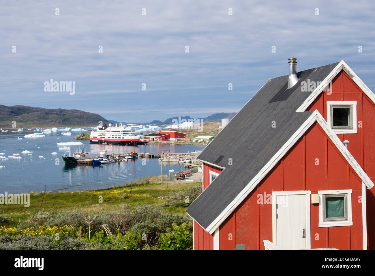 Le groenlandais de bois rouge maison donnant sur port de pêche dans le fjord Tunulliarfik d'icebergs flottant dans l'été. Narsaq Groenland Banque D'Images