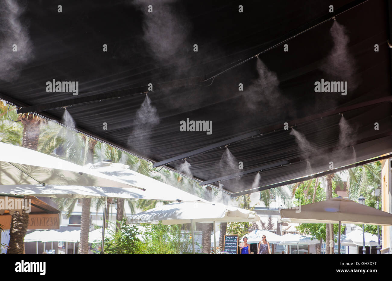 L'eau vaporisée éclaboussures sprinkleurs auvent terrasse au bar afin de refroidir la température de l'été en Espagne Banque D'Images