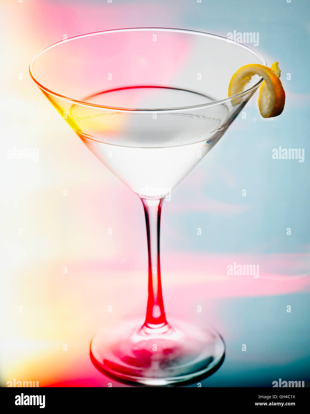 Vue rapprochée d'un verre de martini avec une torsion dans une lumière colorée Banque D'Images
