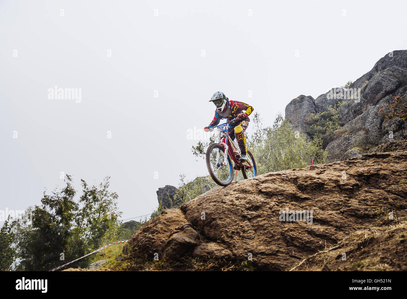 Le jeune pilote masculin athlète, à vélo au bord de la falaise au cours de la descente du championnat national Banque D'Images