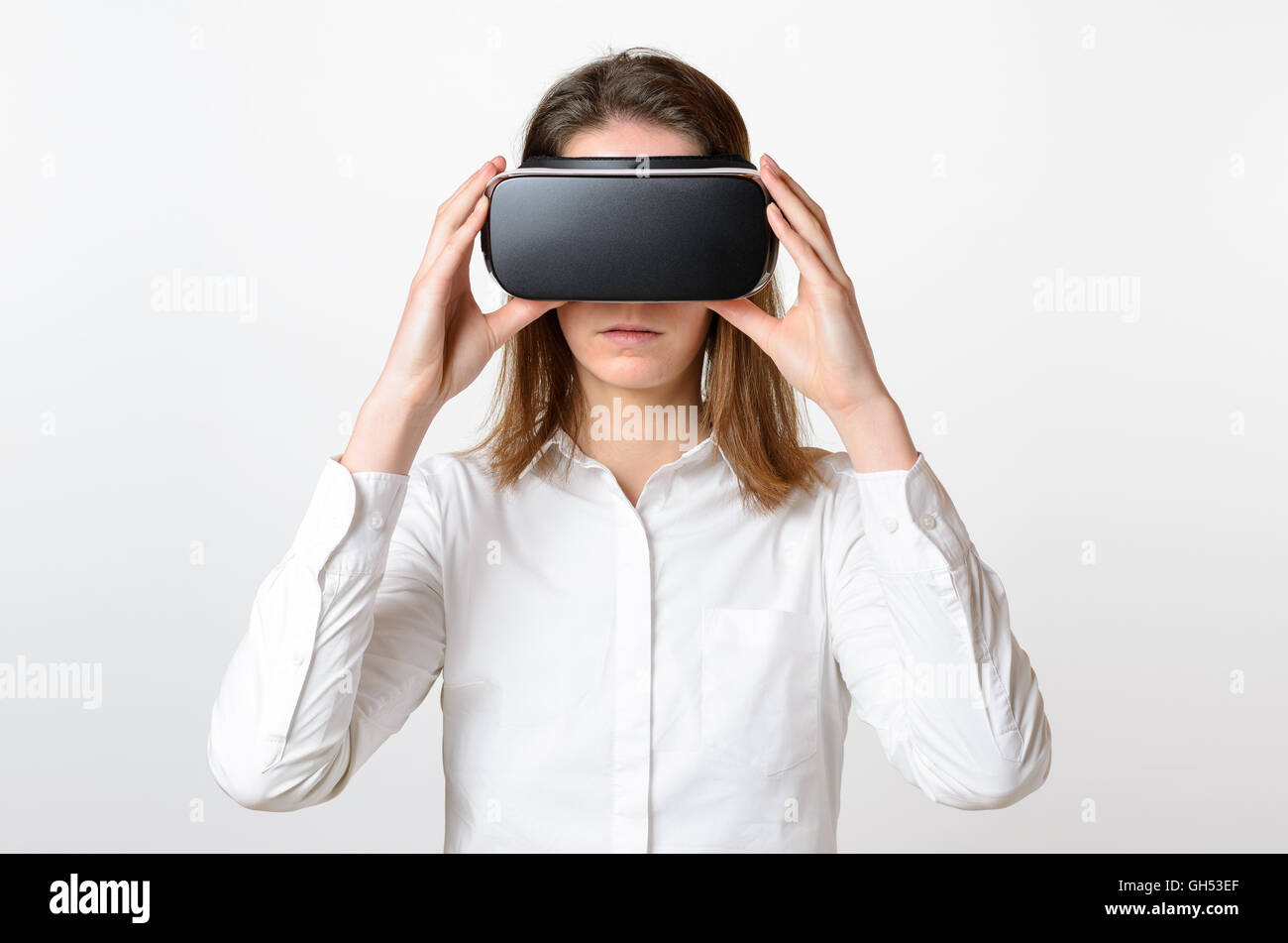 Femme portant un chemisier blanc noir lunettes de réalité virtuelle tient à faire face à l'arrière-plan clair Banque D'Images