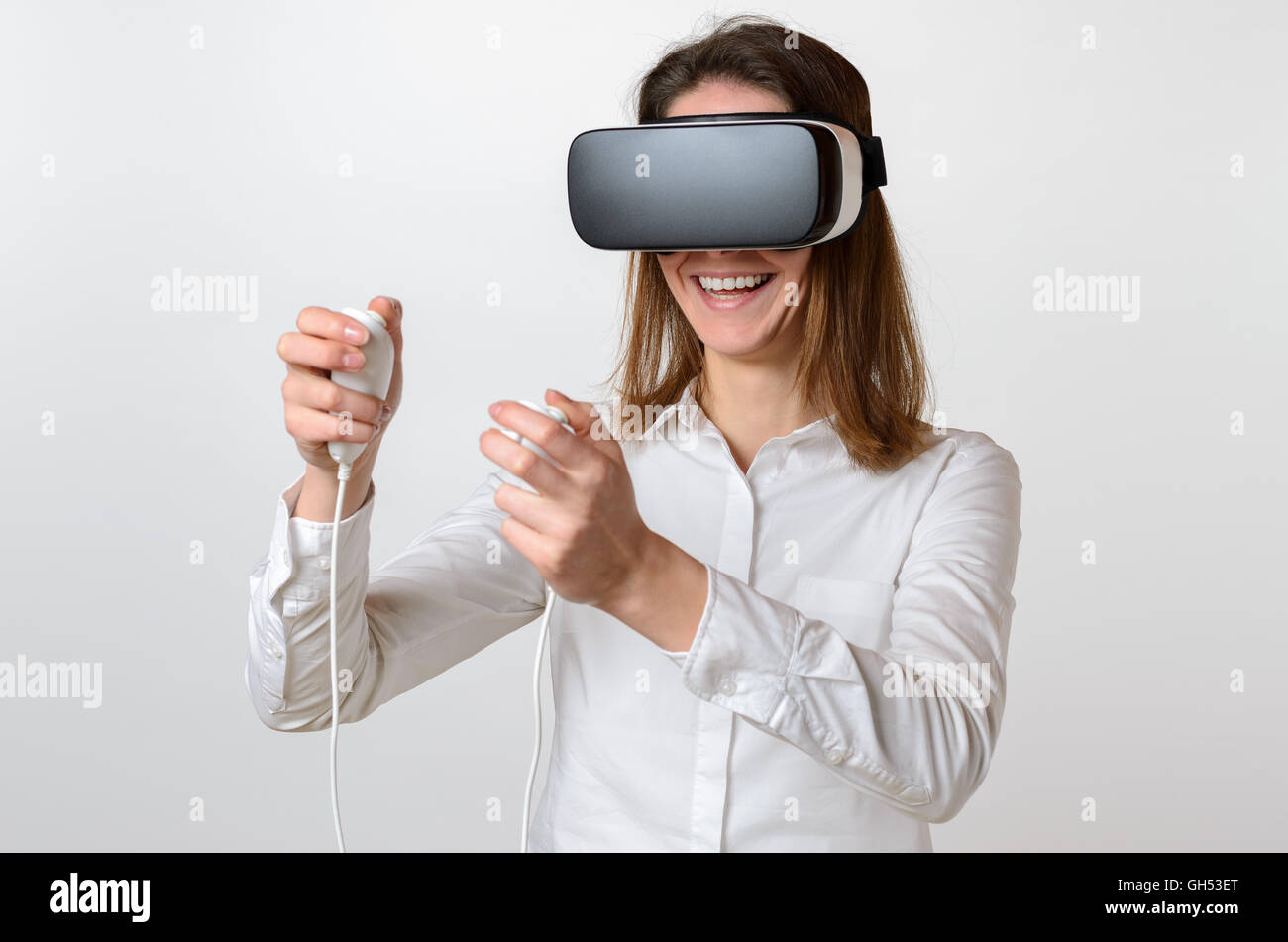 Jeune femme rire unique dans les cheveux foncés et portait une chemise blanche grande réalité virtuelle 3D de l'appareil de visualisation sur le visage et controlli Banque D'Images