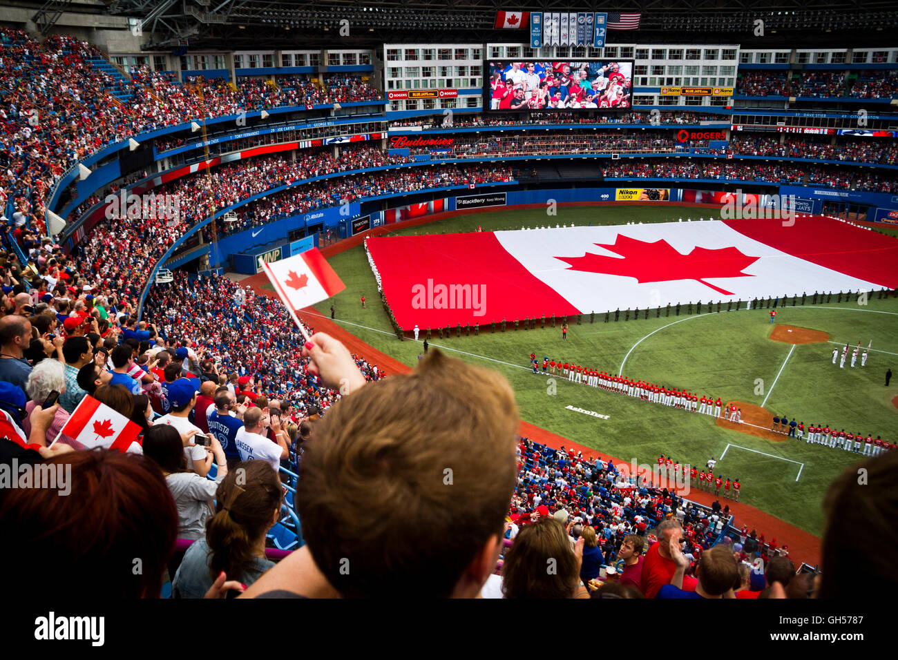 La foule observe un drapeau canadien qui sera mis en place tandis que les hymnes nationaux sont chantés sur la fête du Canada au Centre Rogers de Toronto, Canada. Banque D'Images