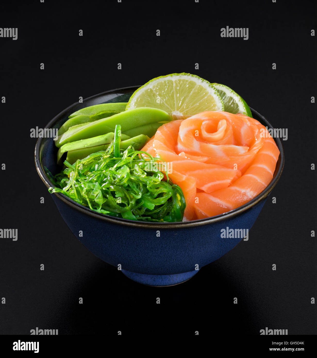Salade d'algues à la japonaise avec du saumon, d'avocat et citron vert sur fond noir Banque D'Images