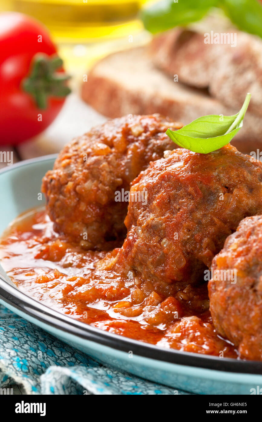 Des boulettes de viande en sauce tomate, tomates fraîches, de pain et d'huile d'olive sur un fond de bois Banque D'Images